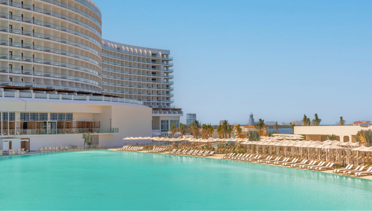 una piscina con tumbonas y sombrillas junto a un edificio