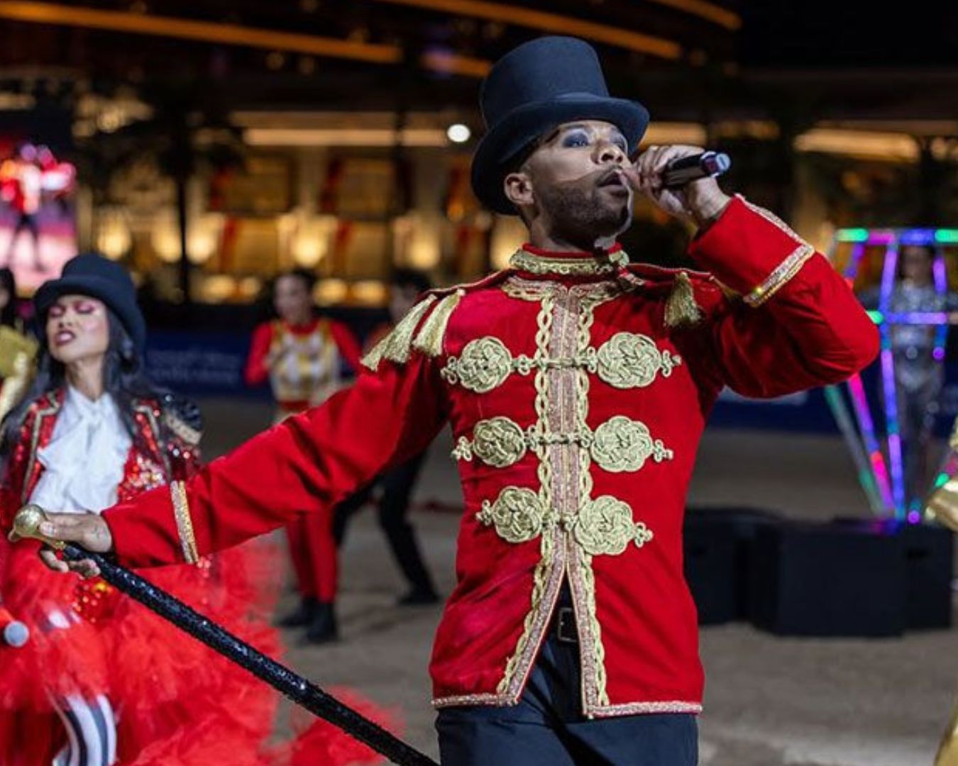 un hombre con una ropa roja cantando a un micrófono