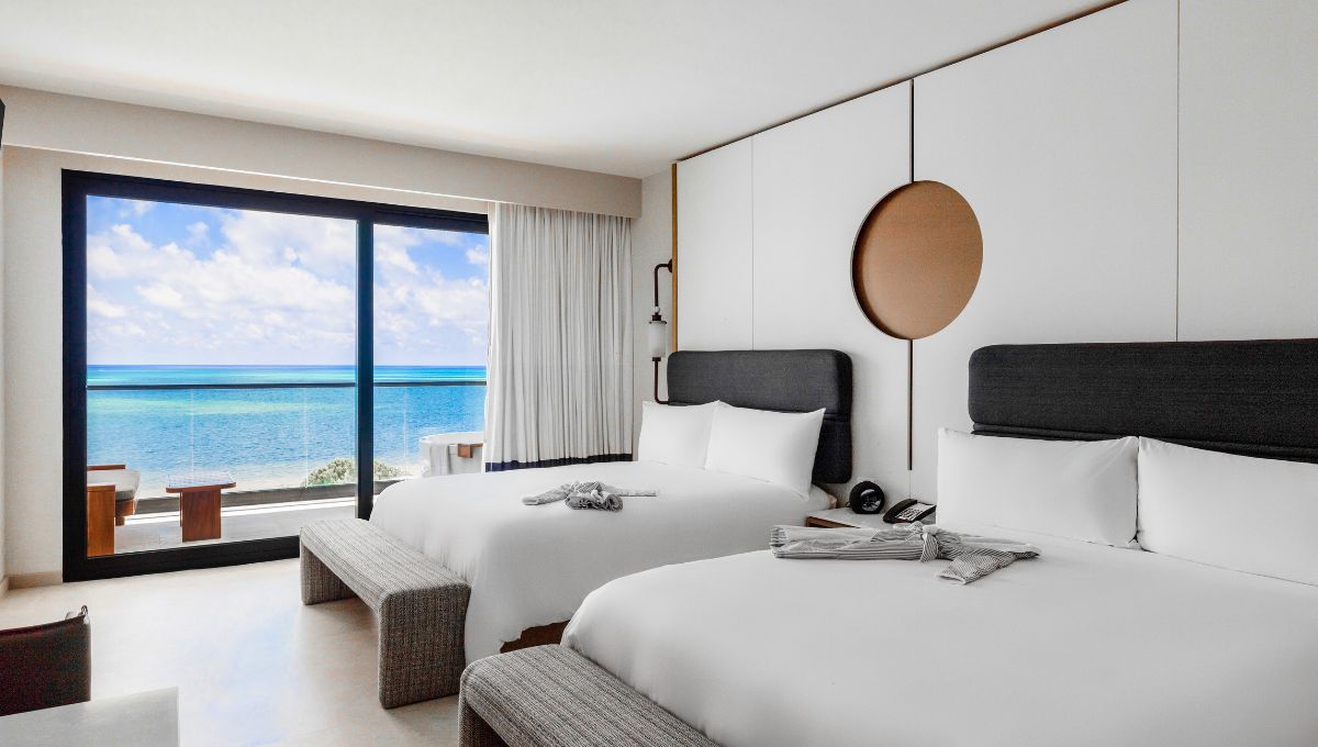 two beds in a room with a view of the ocean