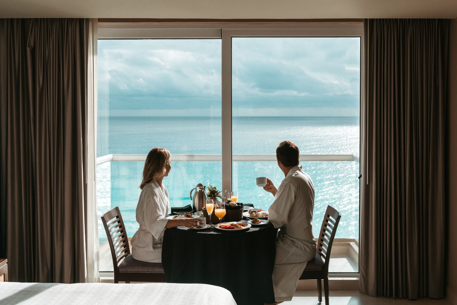 a man and woman sitting at a table with food and drinks
