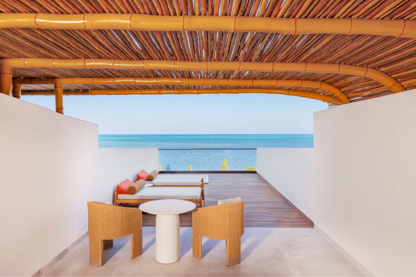 um pátio com mesa e cadeiras e telhado de bambu sobre uma praia